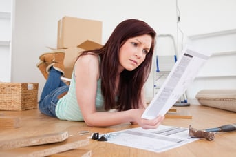 Attractive red-haired female reading a manual before do-it-yourself while lying on the floor at home