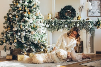 Woman petting dog next to Christmas tree