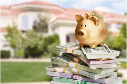 gold piggy bank sitting on top of cash in front of home