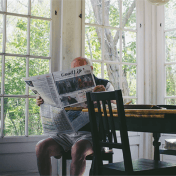 Man reading newspaper at kitchen table