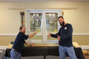 Door installers smiling and giving the thumbs up in front of model size door and frame