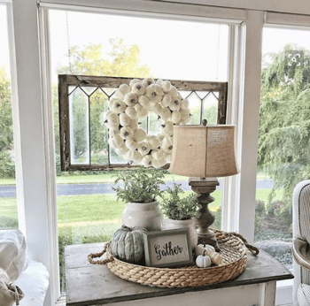 whit pumpkin wreath hanging from window 