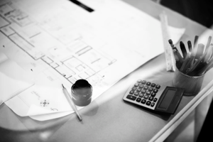 black and white blueprint of home with calculator and pens