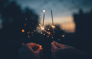 two people holding lit sparklers in the sunset backdrop