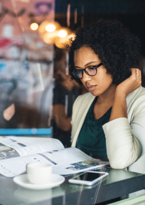 woman reading paper in coffee shop