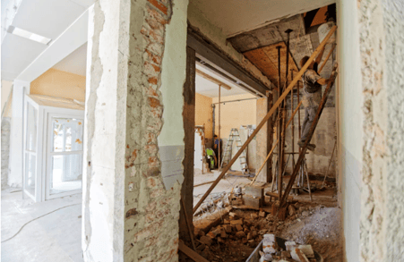 home under renovation with man standing on ladder leading to attic