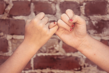 pinky promise in front of a brick wall