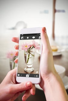 Hand holding smartphone against latte and coffee on table