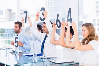 Side view of a group of panel judges holding score signs in a bright office