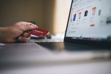 making an online purchase with credit card in hand and laptop open