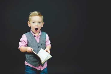 child holding book with a surprised look